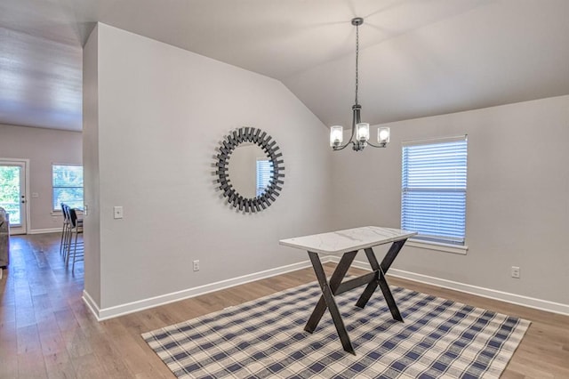 dining room with a chandelier, hardwood / wood-style flooring, and vaulted ceiling