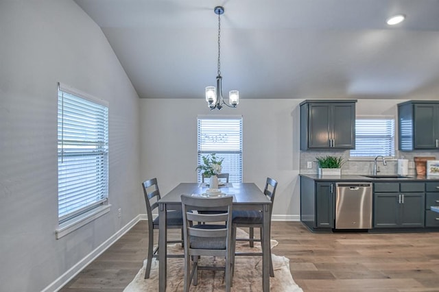 dining room featuring hardwood / wood-style floors, vaulted ceiling, a notable chandelier, and sink