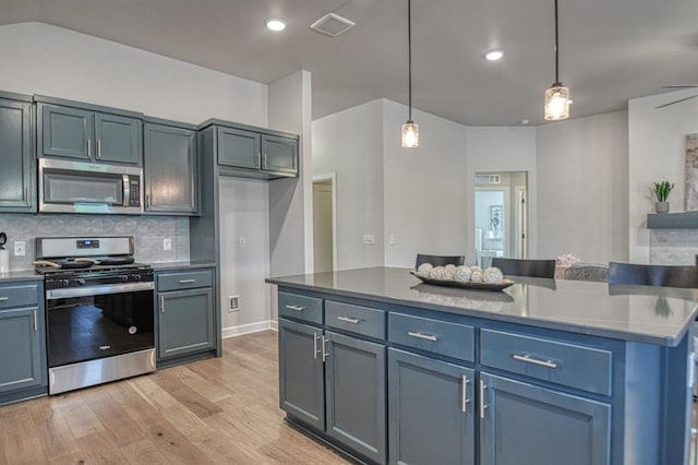 kitchen with stainless steel appliances, light hardwood / wood-style floors, decorative light fixtures, decorative backsplash, and a kitchen island