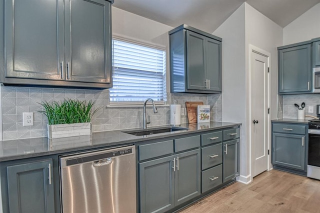 kitchen with tasteful backsplash, sink, stainless steel appliances, and light wood-type flooring