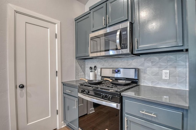 kitchen with decorative backsplash, hardwood / wood-style flooring, gray cabinetry, and appliances with stainless steel finishes