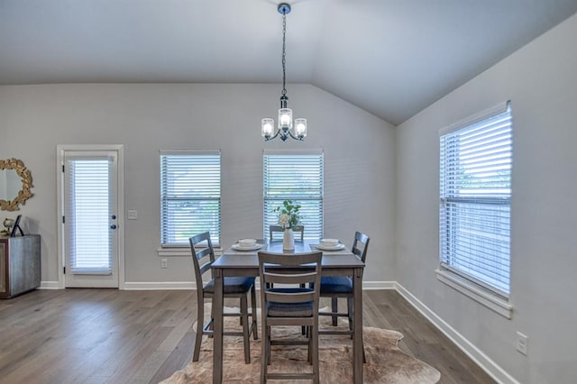 dining space with dark hardwood / wood-style floors, lofted ceiling, and a notable chandelier