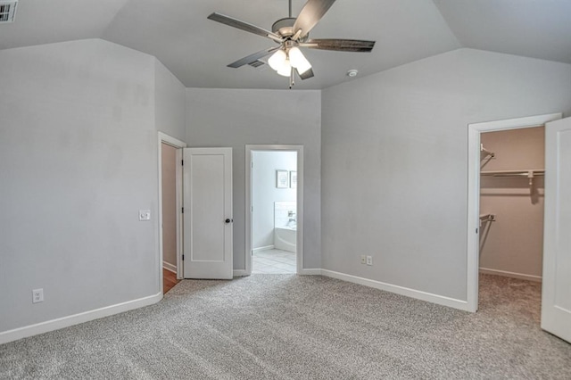 unfurnished bedroom featuring lofted ceiling, ceiling fan, light colored carpet, and a spacious closet