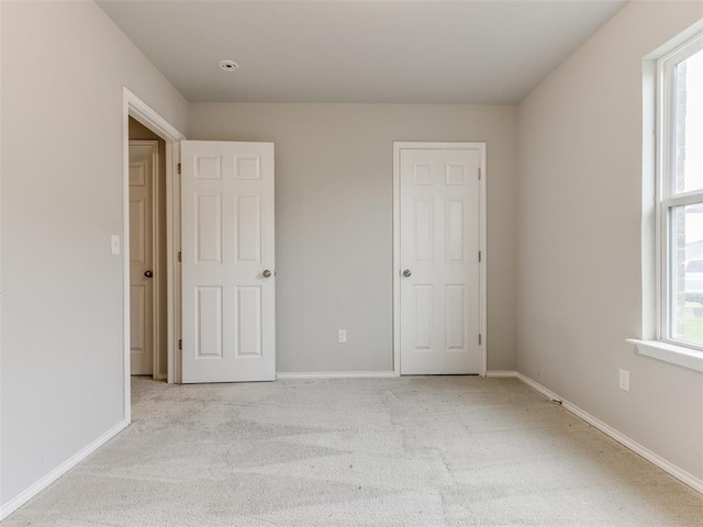 unfurnished bedroom featuring light colored carpet and multiple windows