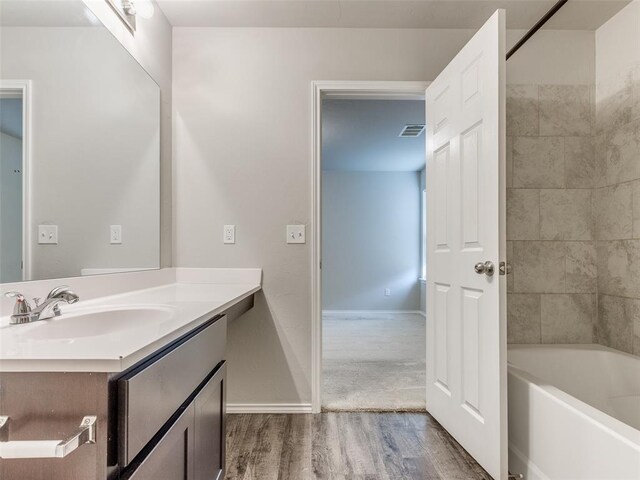 bathroom featuring hardwood / wood-style floors, vanity, and tiled shower / bath combo