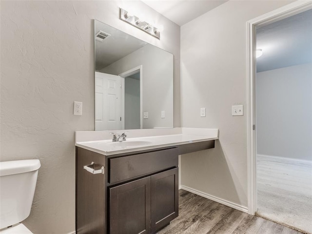 bathroom with hardwood / wood-style floors, vanity, and toilet