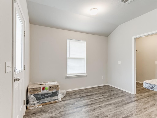 empty room with wood-type flooring and lofted ceiling