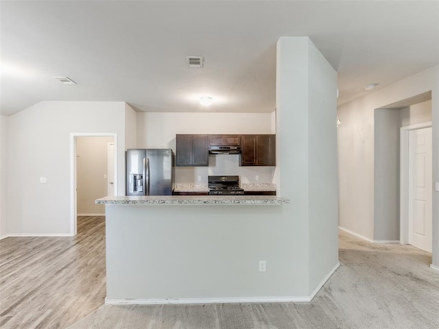 kitchen featuring gas stove, light stone countertops, stainless steel refrigerator with ice dispenser, light colored carpet, and dark brown cabinets