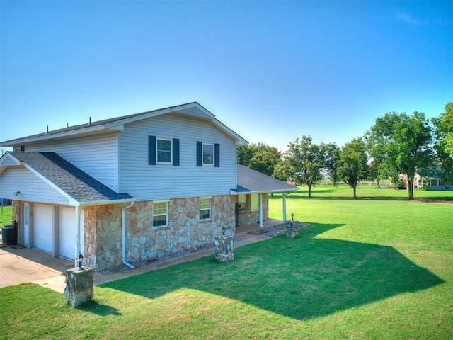 back of house with a yard, a garage, and central air condition unit