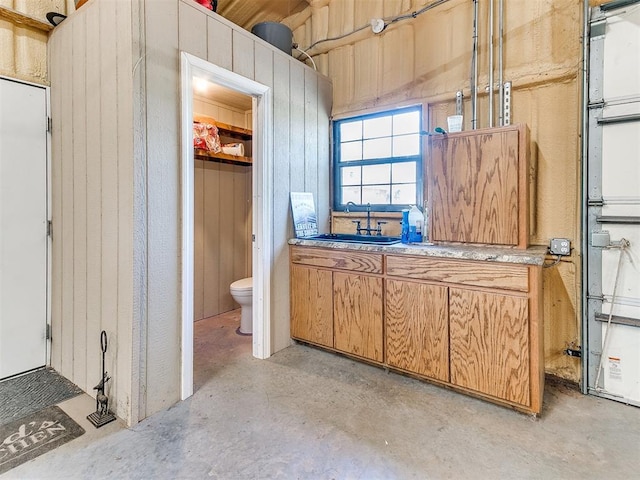 bathroom with toilet, concrete flooring, and sink