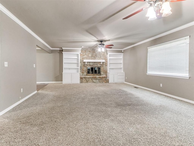 unfurnished living room with carpet flooring, a stone fireplace, crown molding, and built in features