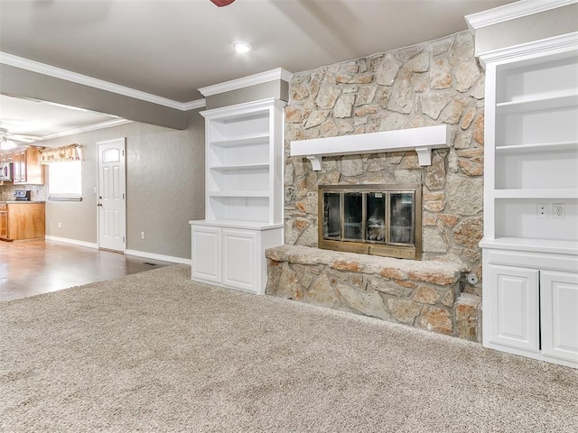 unfurnished living room featuring ornamental molding, built in shelves, ceiling fan, a fireplace, and carpet floors