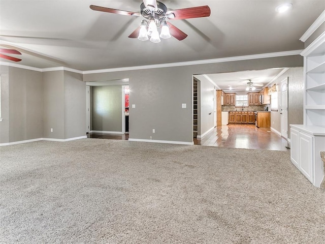 carpeted spare room with ceiling fan, sink, and ornamental molding