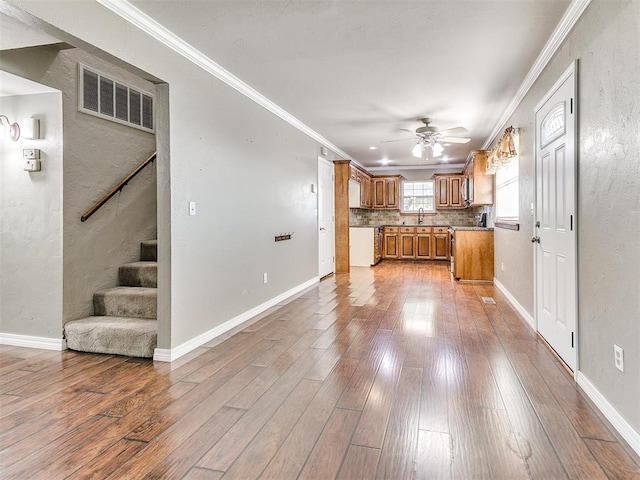 kitchen with hardwood / wood-style floors, ceiling fan, crown molding, and tasteful backsplash