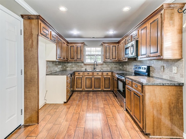 kitchen with backsplash, sink, light hardwood / wood-style flooring, ornamental molding, and stainless steel appliances