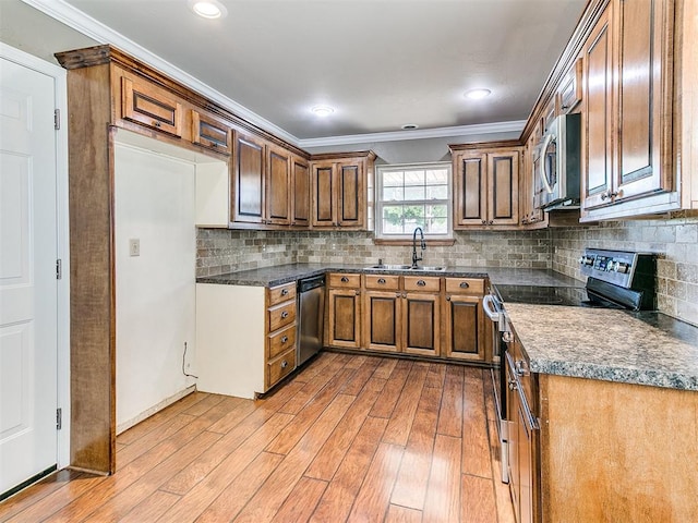 kitchen with appliances with stainless steel finishes, tasteful backsplash, ornamental molding, sink, and light hardwood / wood-style floors