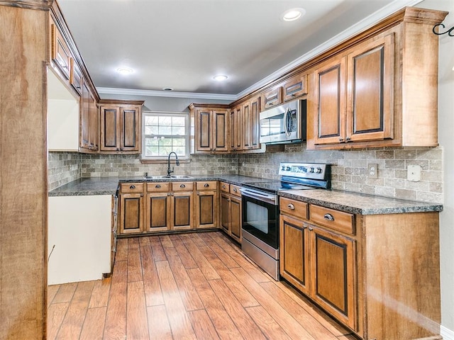 kitchen with appliances with stainless steel finishes, backsplash, crown molding, sink, and light hardwood / wood-style floors