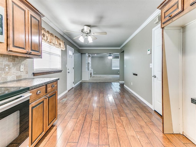 kitchen with backsplash, crown molding, light hardwood / wood-style flooring, ceiling fan, and range