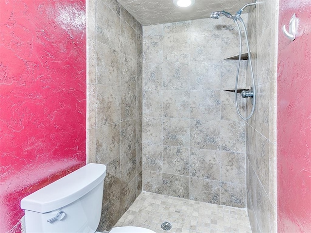 bathroom featuring tiled shower and toilet