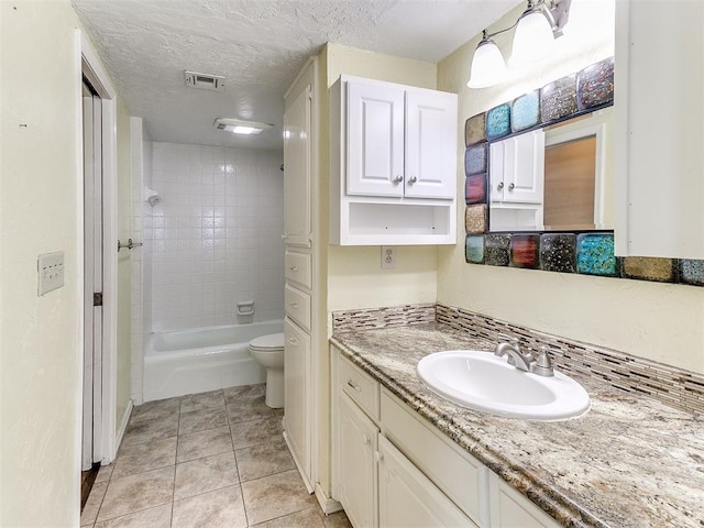 full bathroom featuring tile patterned floors, vanity, a textured ceiling, toilet, and tiled shower / bath