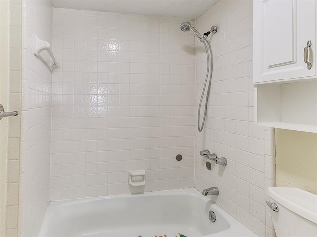 bathroom featuring tiled shower / bath combo and toilet