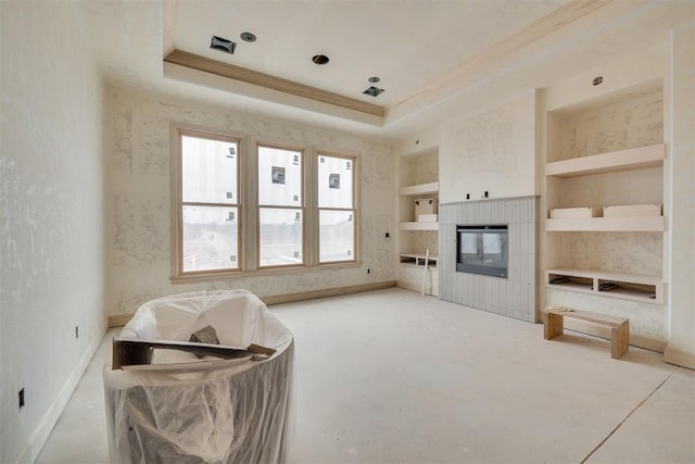 living room with ornamental molding, concrete floors, built in shelves, and a raised ceiling