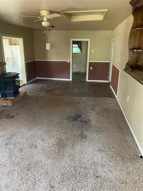 unfurnished living room with a wood stove and ceiling fan