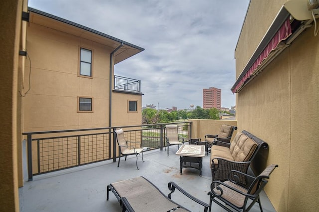 view of patio featuring a balcony and an outdoor living space with a fire pit