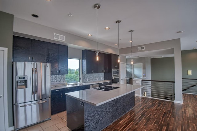 kitchen with appliances with stainless steel finishes, light wood-type flooring, backsplash, decorative light fixtures, and a center island