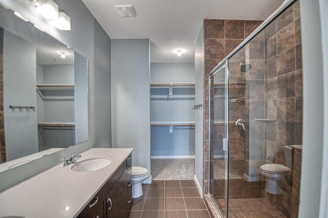 bathroom featuring tile patterned floors, vanity, a shower with shower door, and toilet