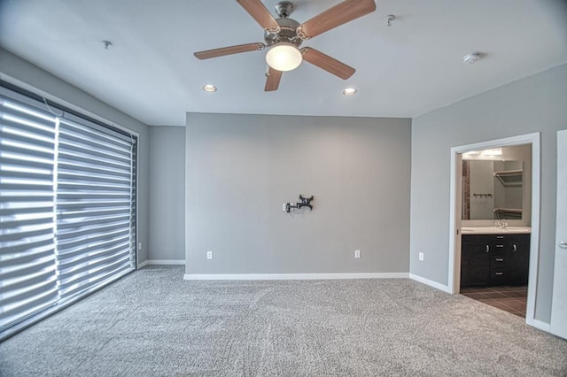 unfurnished bedroom with dark colored carpet, ceiling fan, sink, and connected bathroom