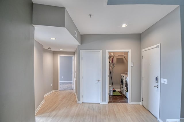 hall with separate washer and dryer and light hardwood / wood-style floors