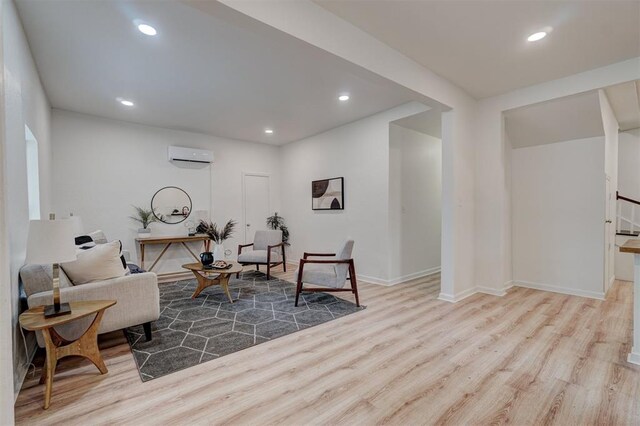 living area with light hardwood / wood-style floors and an AC wall unit