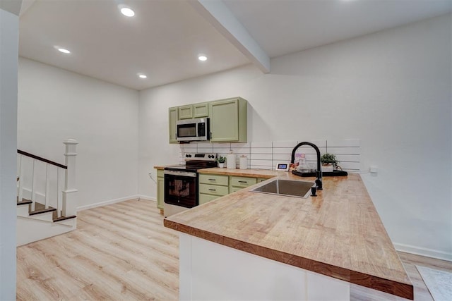 kitchen with kitchen peninsula, green cabinets, range with electric cooktop, and sink