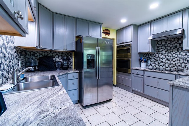 kitchen with light stone countertops, appliances with stainless steel finishes, tasteful backsplash, sink, and gray cabinets