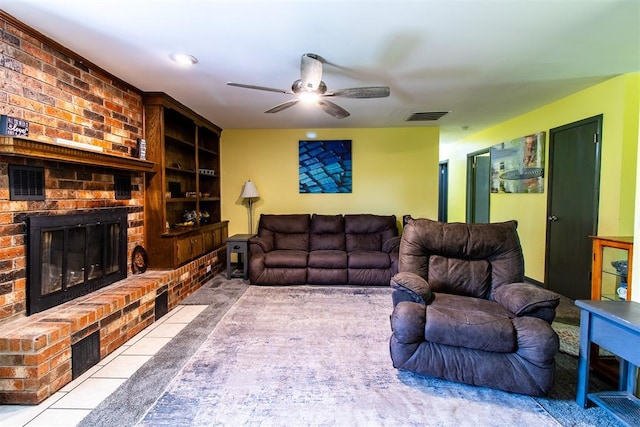 living room featuring built in shelves, ceiling fan, a fireplace, and light tile patterned floors