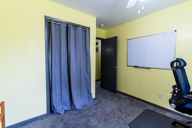 exercise room with ceiling fan and dark colored carpet