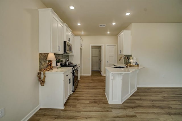 kitchen featuring white cabinets, appliances with stainless steel finishes, hardwood / wood-style flooring, and sink