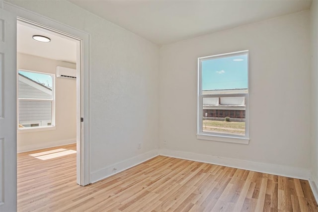 unfurnished room featuring light wood-type flooring and a wall unit AC