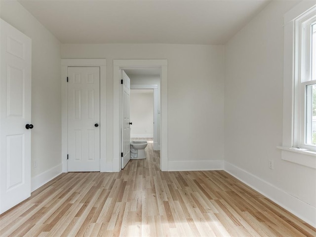 unfurnished bedroom featuring light hardwood / wood-style floors and connected bathroom