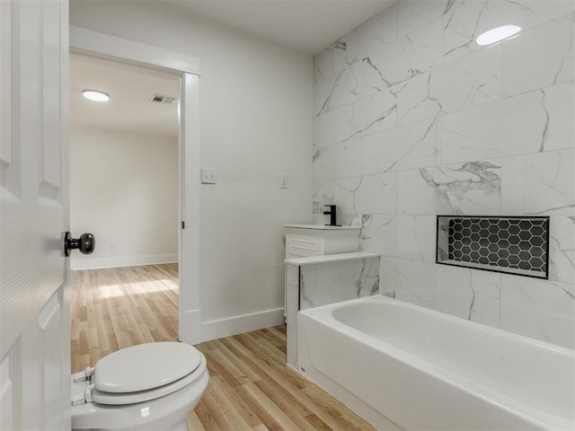 bathroom featuring hardwood / wood-style floors, toilet, and a bathing tub