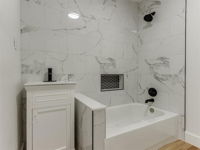 bathroom with wood-type flooring, vanity, and tiled shower / bath