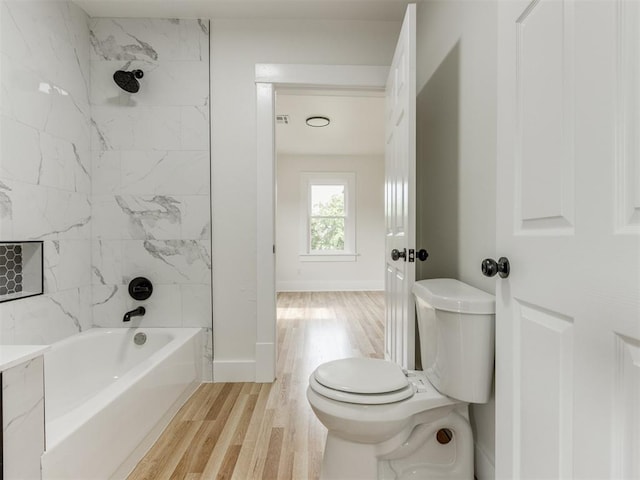 bathroom featuring toilet, wood-type flooring, and tiled shower / bath