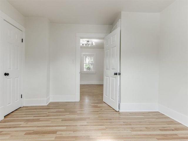 spare room with light wood-type flooring and an inviting chandelier