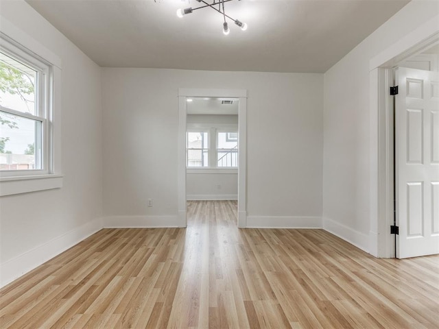 empty room featuring an inviting chandelier and light hardwood / wood-style flooring