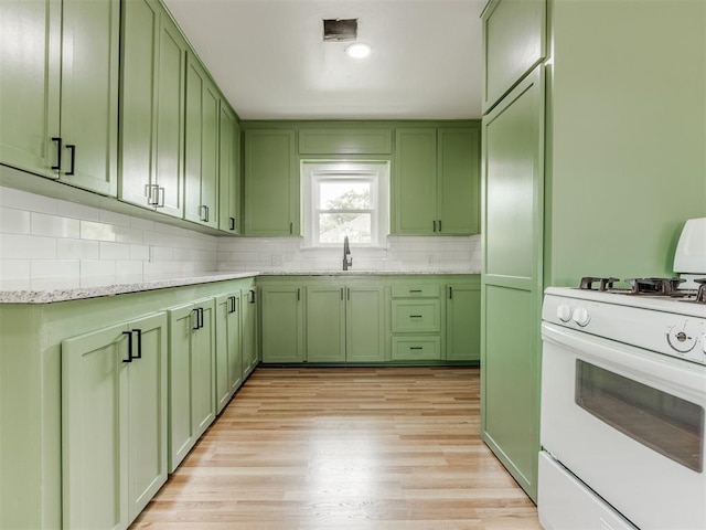 kitchen featuring sink, light stone counters, white range with gas stovetop, green cabinetry, and light wood-type flooring