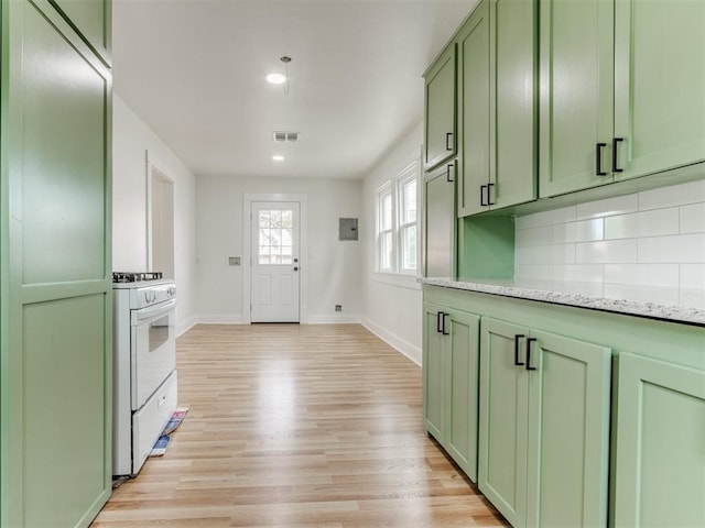 kitchen with white gas range, light stone counters, light hardwood / wood-style floors, decorative backsplash, and green cabinetry