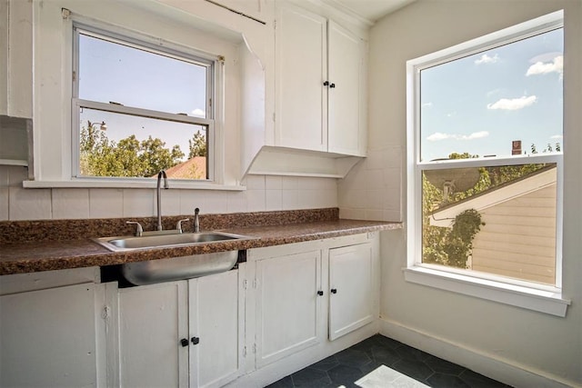 kitchen with white cabinets, tasteful backsplash, dark tile patterned floors, and sink