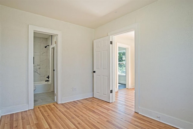 unfurnished bedroom featuring ensuite bathroom and light hardwood / wood-style floors