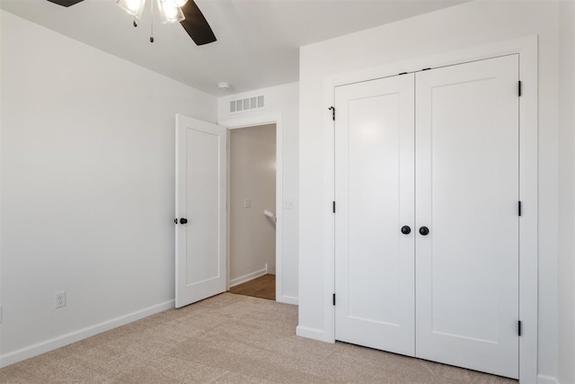 unfurnished bedroom featuring ceiling fan, light carpet, and a closet